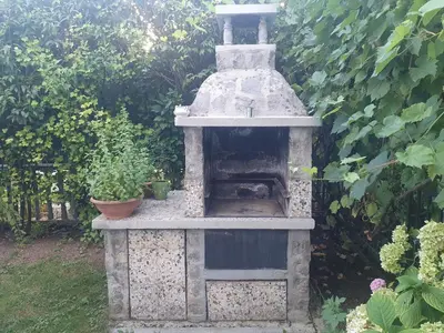 an outdoor pizza oven in a garden with plants at Green Garden Home in Cerknica