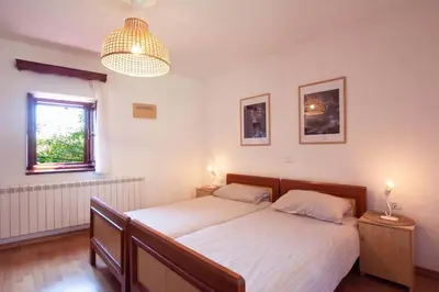 a bedroom with a bed with white sheets and a window at Apartmaji Žnidarčič in Divača
