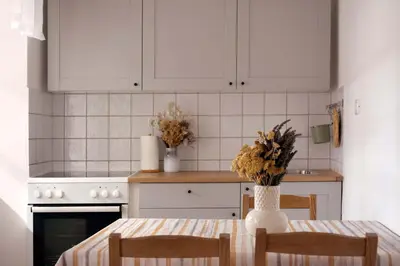 a kitchen with white cabinets and a table with chairs at Apartmaji Žnidarčič in Divača