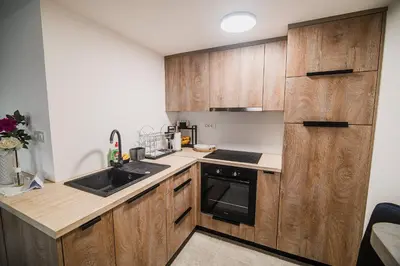 a kitchen with wooden cabinets and a sink at Apartment Trta with Vineyard View in Bistrica ob Sotli