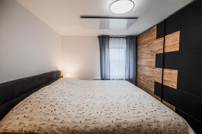 a bedroom with a large bed with a wooden wall at Apartment Trta with Vineyard View in Bistrica ob Sotli