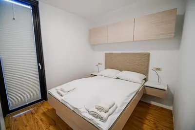 a bedroom with a bed with white sheets and a window at Glamping Maleric with Natural Pool in Dragatuš