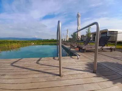a wooden deck with a bench and a pool of water at Glamping Maleric with Natural Pool in Dragatuš