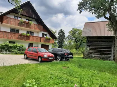 two cars parked in front of a house at Encijan in Bohinj