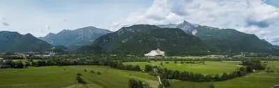a large green field with mountains in the background at Hiša Krn in Kobarid