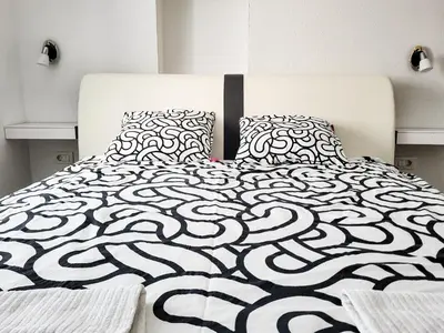 a bed with a black and white comforter and pillows at Stara Pošta Apartment 7 in Grosuplje