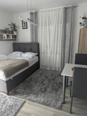 a bedroom with a bed and a window at Studio apartman DINO z balkonom in Rogatec