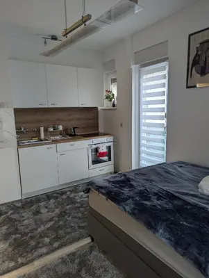a kitchen with white cabinets and a counter top at Studio apartman DINO z balkonom in Rogatec