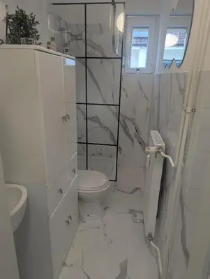 a white bathroom with a toilet and a sink at Studio apartman DINO z balkonom in Rogatec