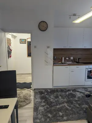 a kitchen with white cabinets and a clock on the wall at Studio apartman DINO z balkonom in Rogatec