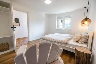 a white bedroom with a bed and two chairs at Hidden Corner in Žirovnica