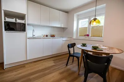 a kitchen with white cabinets and a table and chairs at Hidden Corner in Žirovnica