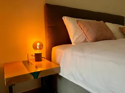 a bed with a lamp on a table next to a bed at Cozy & Chic - Apartment with a private patio in Kobarid