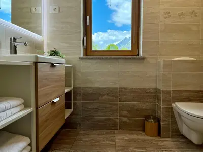 a bathroom with a sink and a toilet and a window at Cozy & Chic - Apartment with a private patio in Kobarid