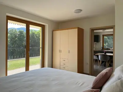 a bedroom with a bed and a sliding glass door at Cozy & Chic - Apartment with a private patio in Kobarid
