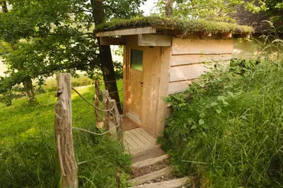 a wooden out house with stairs leading up to it at Lakeside Glamping Tents Mažijev Grič in Gradišče pri Lukovici
