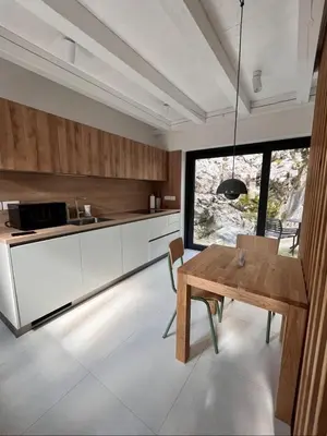 a kitchen with white cabinets and a wooden table at Up and above in Kobarid