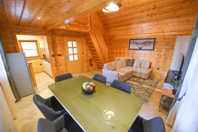 a living room with a table and chairs in a cabin at Wooden Cottage Baznik with Hot Tub in Cerklje ob Krki