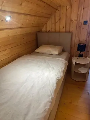 a bedroom with a bed in a wooden cabin at Wooden Cottage Baznik with Hot Tub in Cerklje ob Krki