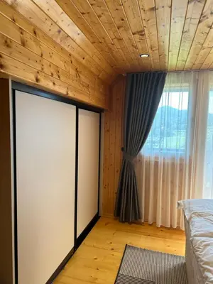 a bedroom with a bed and a wooden ceiling at Wooden Cottage Baznik with Hot Tub in Cerklje ob Krki