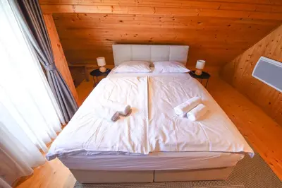 a bed in a wooden room with two towels on it at Wooden Cottage Baznik with Hot Tub in Cerklje ob Krki