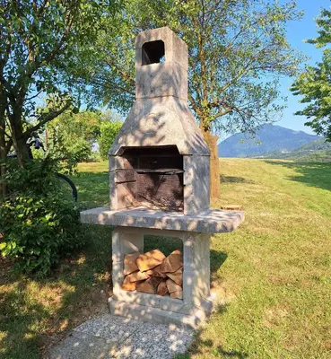 a stone oven with a pile of wood in a field at Rural Retreat- Kmečki oddih in Poljčane