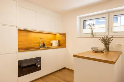 a kitchen with white cabinets and a wooden counter top at Apartmaji Klavdija in Ljubljana