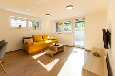 a living room with a yellow couch and a tv at Apartmaji Klavdija in Ljubljana