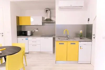 a kitchen with yellow cabinets and a table at Apartma RO-ZE in Bistrica ob Sotli