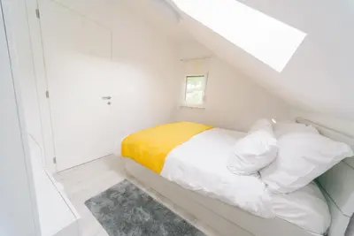 a white bedroom with a bed with a yellow blanket at Apartma RO-ZE in Bistrica ob Sotli