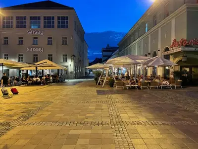 an empty street with tables and umbrellas and buildings at Janko's house in Maribor