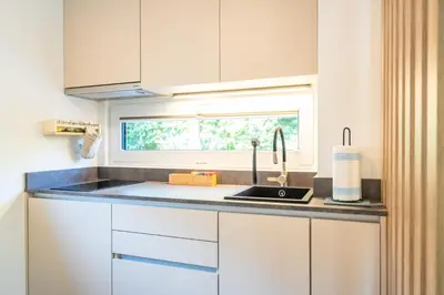 a kitchen with white cabinets and a sink and a window at Private House - Serenity home in Lokev