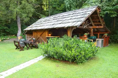a log cabin with a table and a bench in a yard at Vila Edelweiss Rooms&App Kranjska Gora in Kranjska Gora