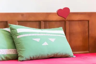 a pillow on a bed with a heart on the headboard at Apartments Petacova Hiša in Kranjska Gora