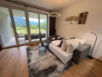 a living room with a couch and a large window at Riverstone Retreat Bovec in Bovec