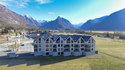 an aerial view of a building with mountains in the background at Riverstone Retreat Bovec in Bovec