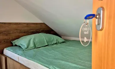 a bed with a wooden headboard with a green pillow at Bled Lesce station rooms and depo in Lesce