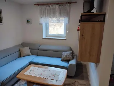 a living room with a blue couch and a window at Apartmaji Stara Šola in Bohinjska Bistrica