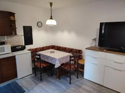 a kitchen with a table with chairs and a tv at Apartmaji Stara Šola in Bohinjska Bistrica