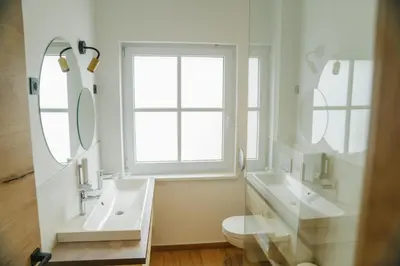 a white bathroom with two sinks and a window at Sobe rooms JELEN JELENOV GREBEN in Podčetrtek