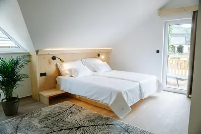 a bedroom with a bed with white sheets and a window at Sobe rooms JELEN JELENOV GREBEN in Podčetrtek