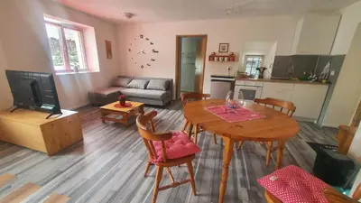 a living room with a table and a kitchen at Idiličen apartma in Kamna Gorica