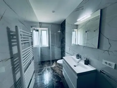 a white bathroom with a sink and a mirror at Rebecca's Apartment in Radovljica
