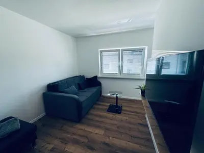 a living room with a blue couch and two windows at Rebecca's Apartment in Radovljica