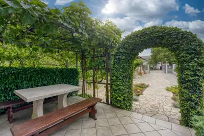 an archway with a bench in a garden at Cesar's Karst Estate in Sežana