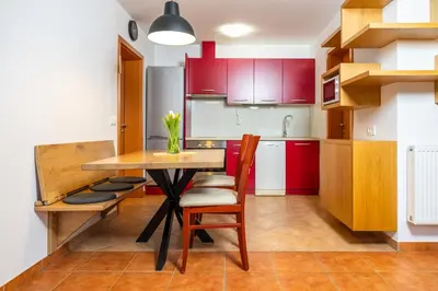 a kitchen with red cabinets and a wooden table and chairs at Apartment Markič in Bohinj