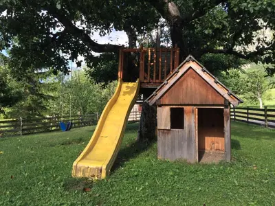 a wooden play house with a slide on a tree at Apartment Markič in Bohinj
