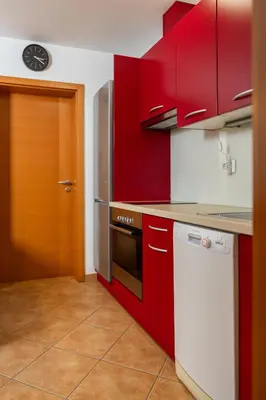 a kitchen with red cabinets and a white dishwasher at Apartment Markič in Bohinj