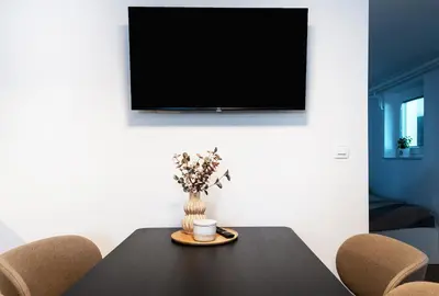 a table with a vase of flowers and a tv on a wall at Mojca's nest apartment in Mengeš
