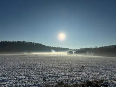 a snow covered field with the sun in the background at Mojca's nest apartment in Mengeš